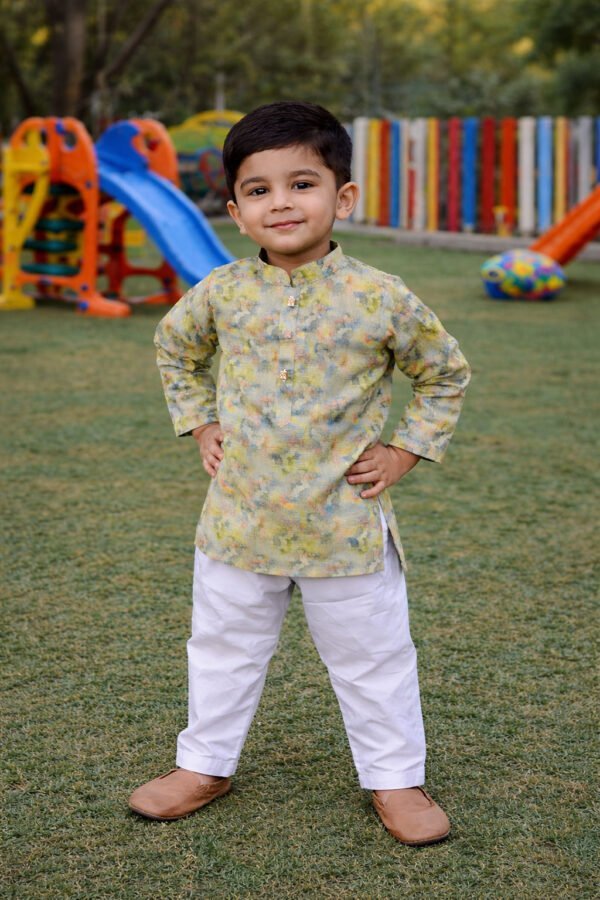 Cute boy wearing pastel floral kurta and white pajama, standing confidently outdoors in a colorful p.