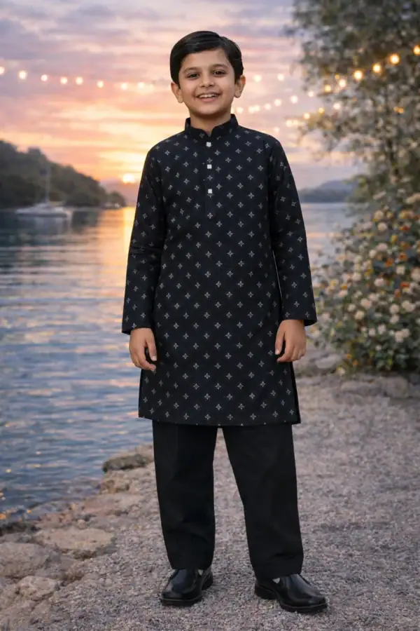 Boy wearing a black diamond pattern kurta and pajama set outdoors at sunset.